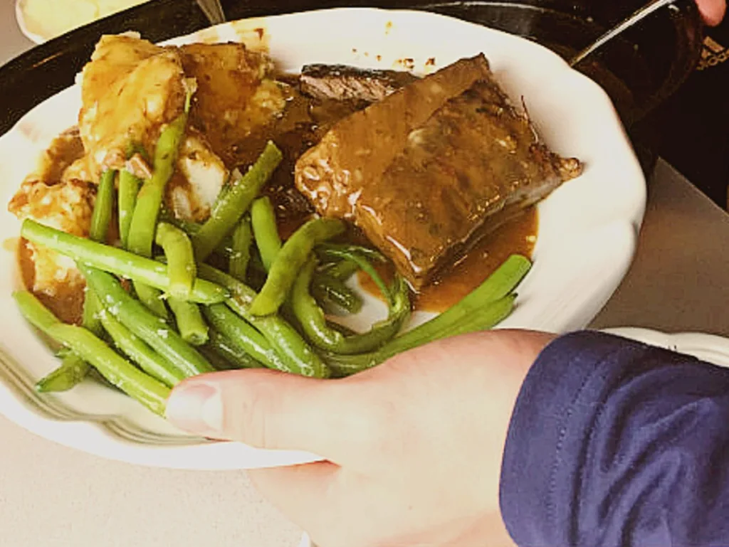 oven baked steak with mashed poatoes, gravy and green beans on a plate carried by our grandson