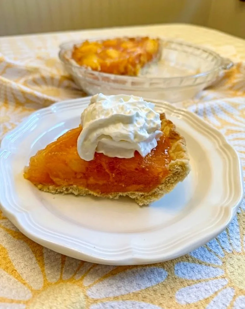 fresh peach pie topped with whipped cream ready to serve from my ktchen table
