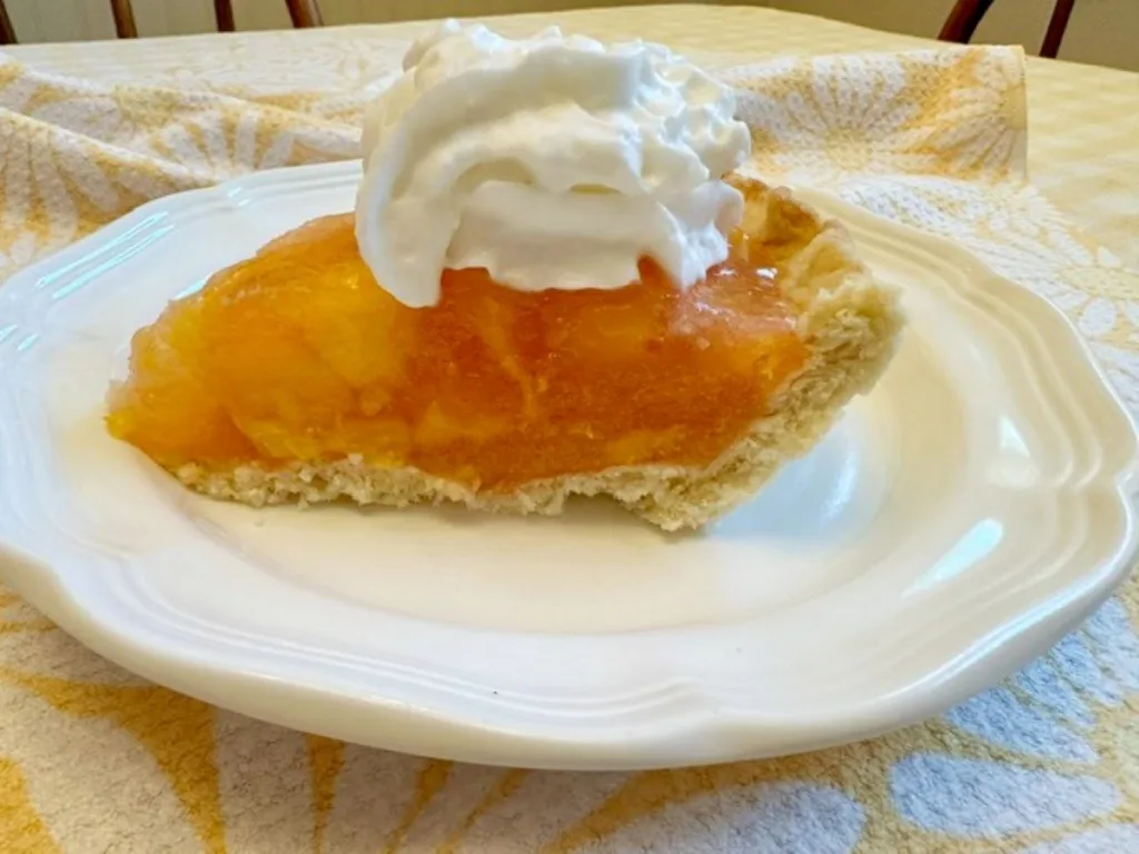 peach pie on white plate with whipped cream