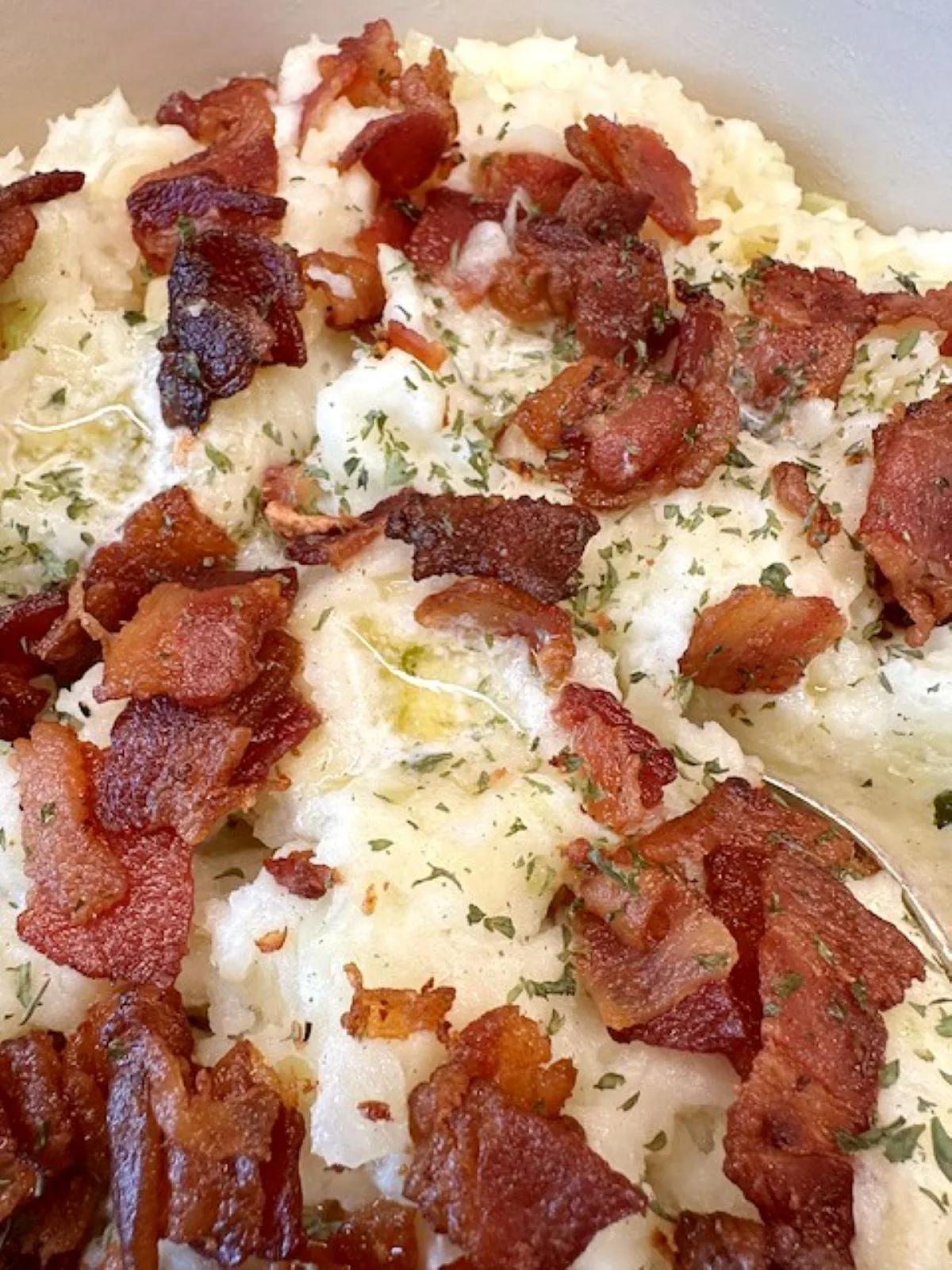 Close-up of creamy Irish Colcannon topped with sizzling bacon and melted butter — classic mashed potatoes with cabbage made the Irish way.