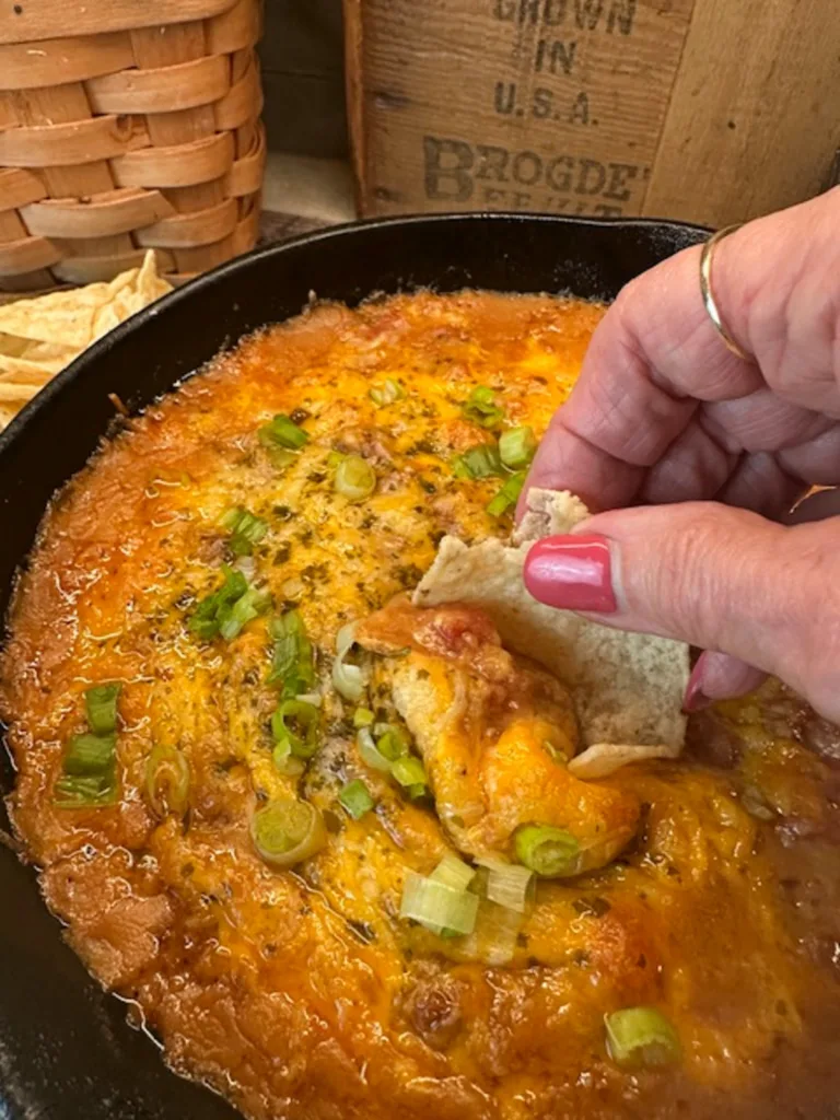 easy 3-ingredient bean dip for game day served in cast-iron skillet with ooey gooey melted cheese