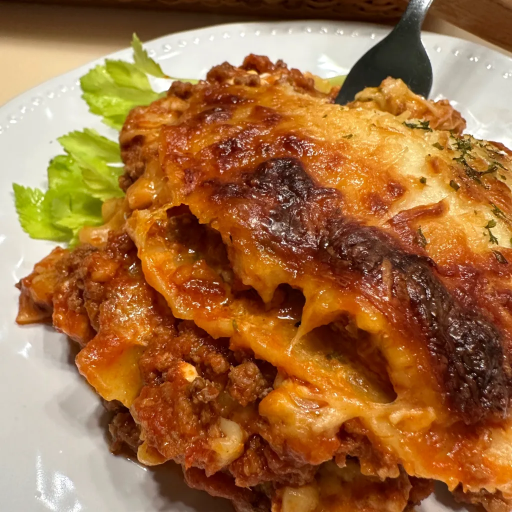 one piece of plated lasagna with garnish and a fork