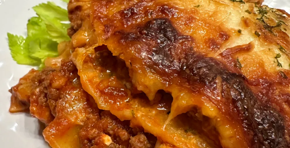 a serving of overnight lasagna on a white plate with garnish and fork