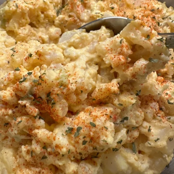 A bowl of old fashioned potato salad garnished with parsley and paprika