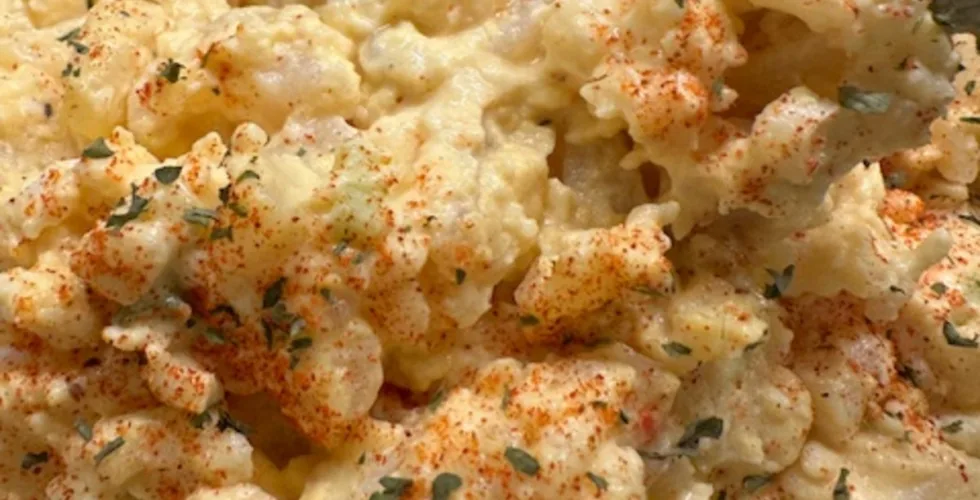 A bowl of old fashioned potato salad garnished with parsley and paprika