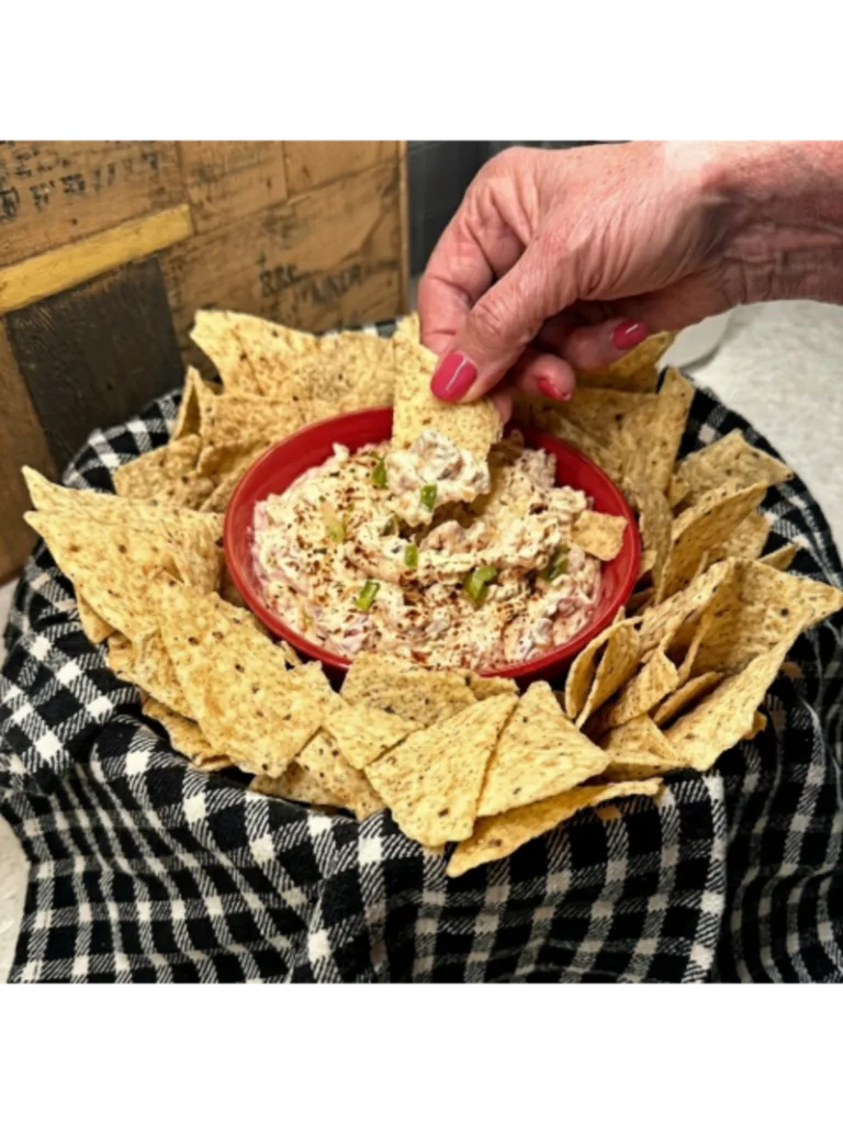 Dipping a tortilla chip into a bowl of boat dip

